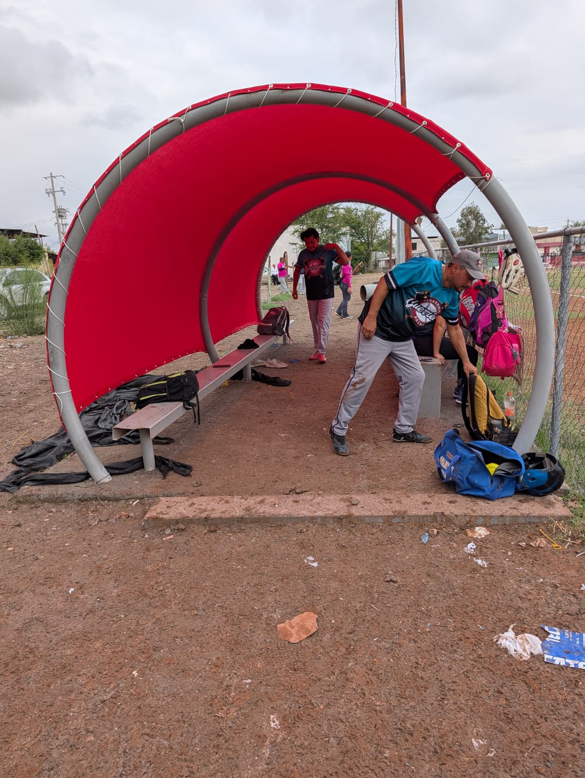 Estructura de arco rojo con mallasombra en campo de béisbol